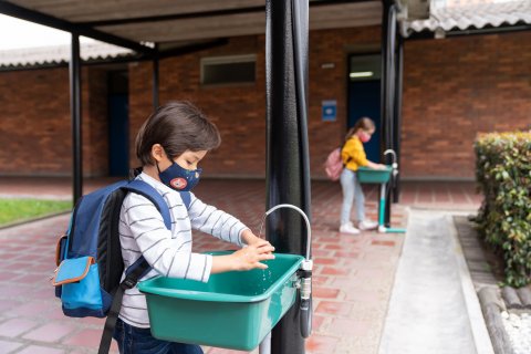 Child in mask washing hands